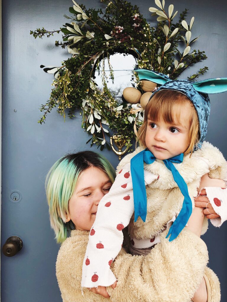 ребенок в шапке с ушками и праздничный пасхальный венок