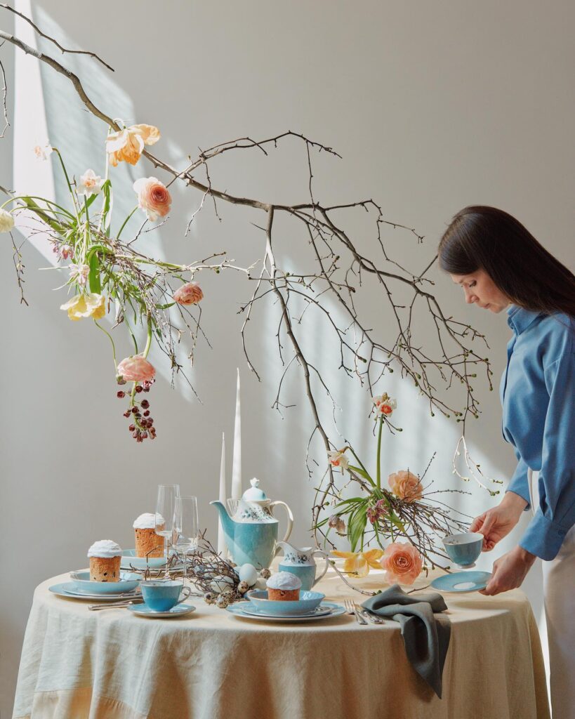 девушка и сервированный стол с голубой посудой и персиковыми цветами