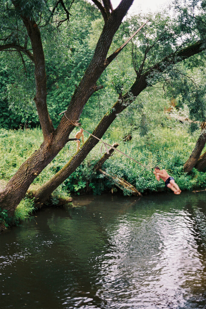 мужчина и дети прыгают с тарзанки в реку