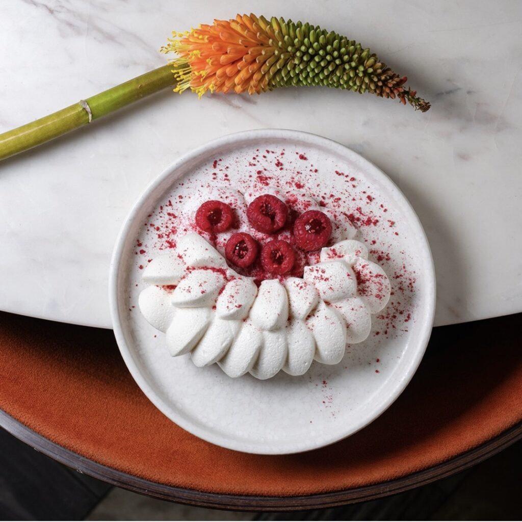 белое суфле с ягодами в тарелке и экзотическйи цветок