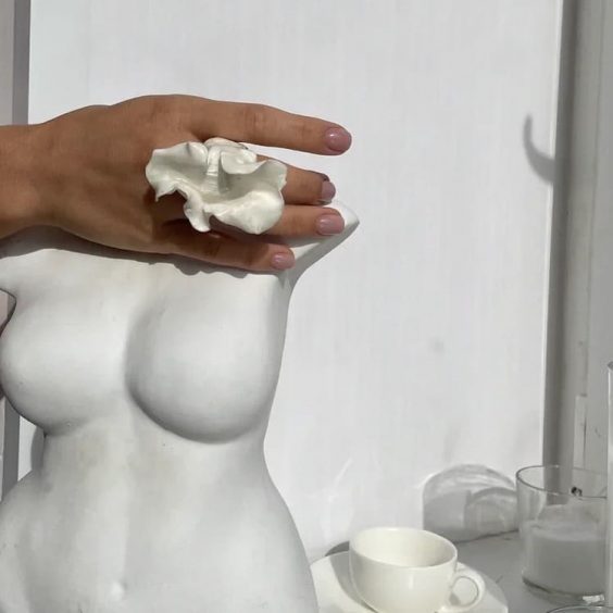 бюст женщины из гипса и рука с массивным белым кольцом из керамики